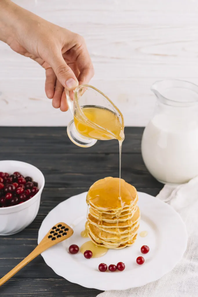 close up human hand holding honey pancake stacked