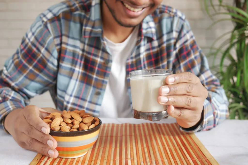young man hand hold glass milk almond nut