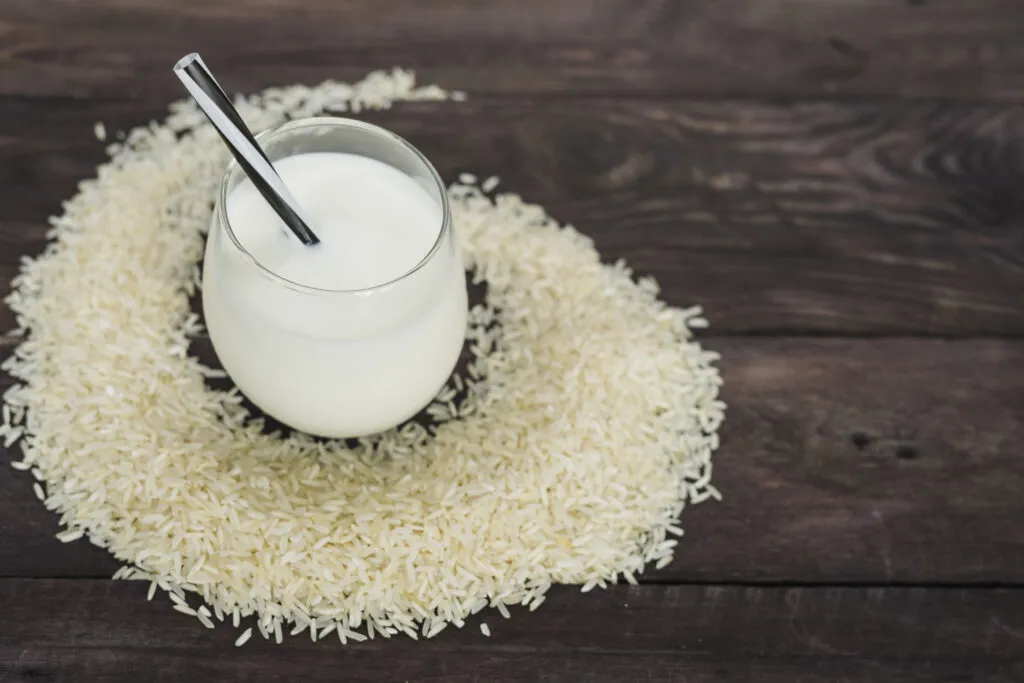 glass homemade rice milk decorated with white raw rice wooden table