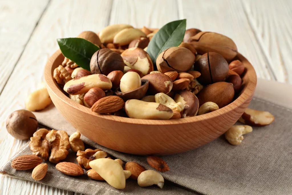 bowl with different tasty nuts white wooden