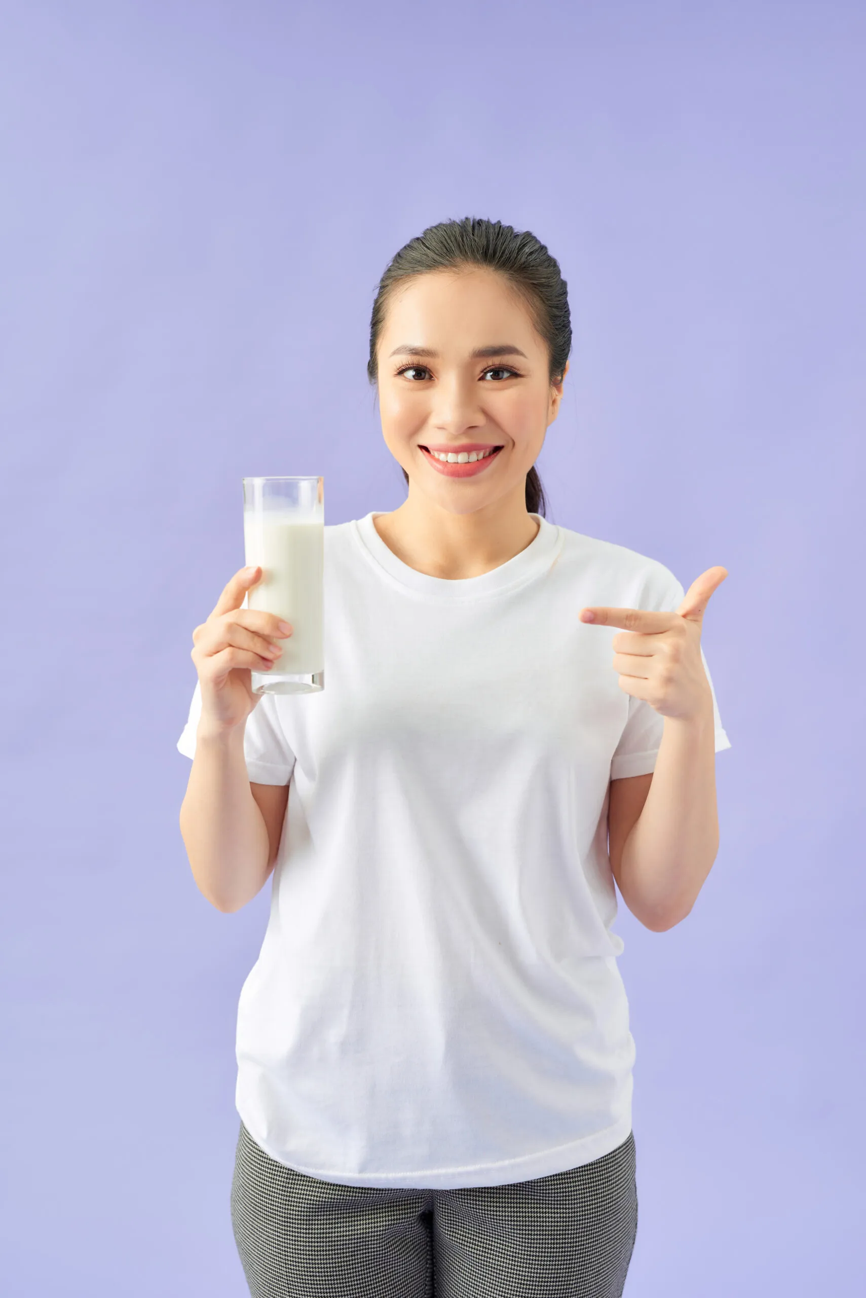 Người phụ nữ mỉm cười cầm ly sữa hạt, làn da sáng mịn tự nhiên