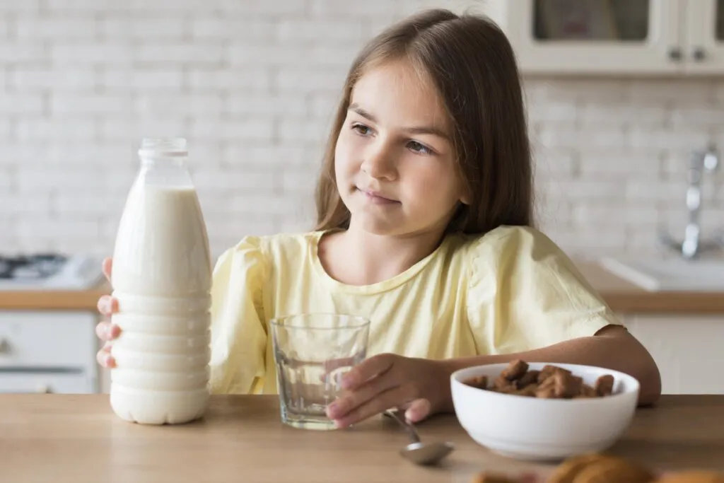 medium shot girl holding milk bottle