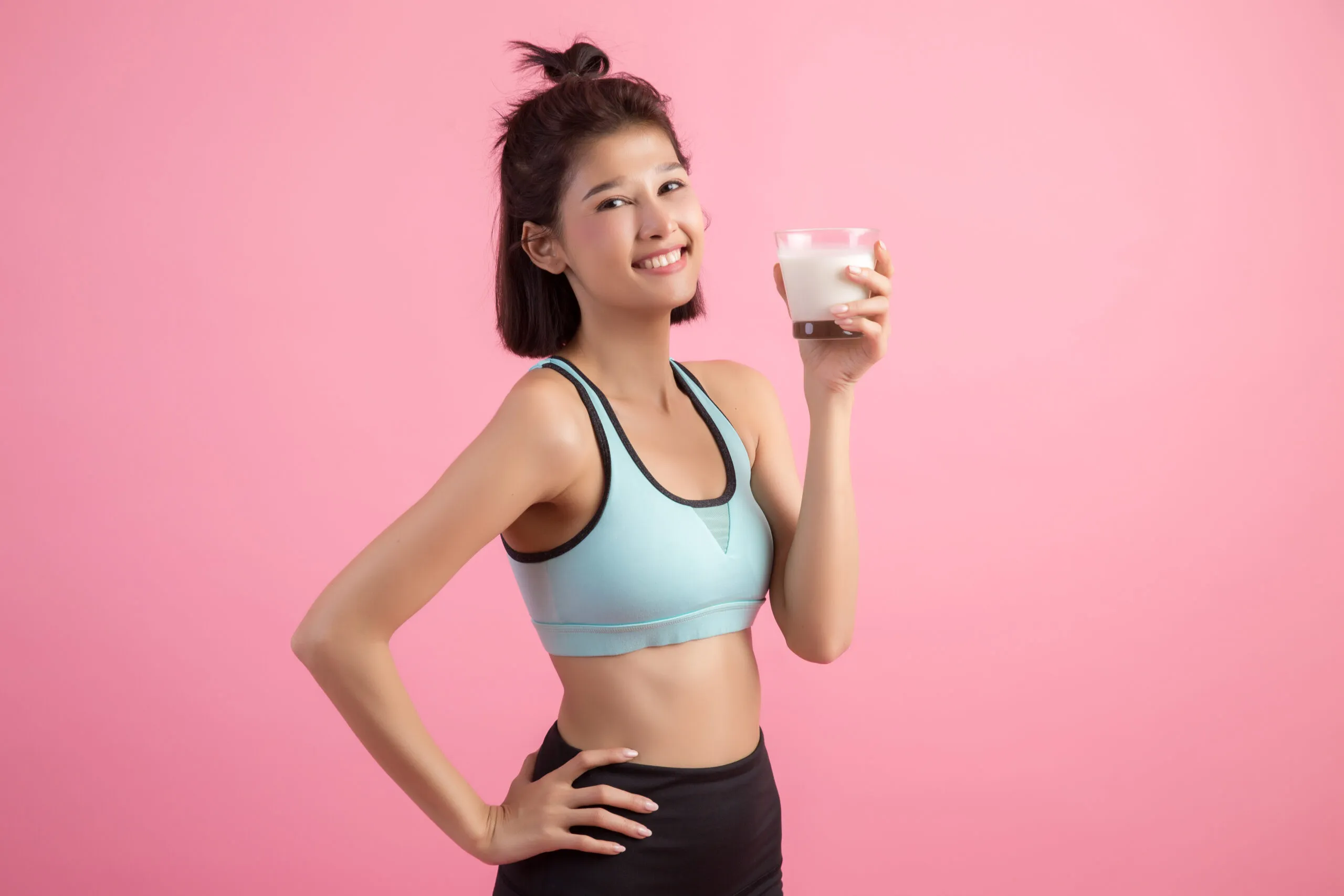 Cô gái trẻ cầm ly sữa hạt sau khi tập luyện thể thao.